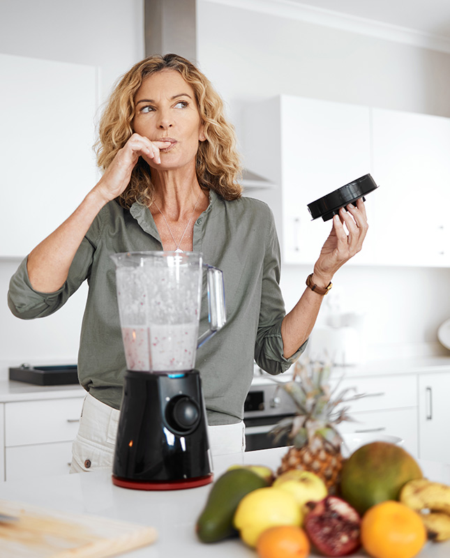 Junge Frau mit Früchten und Mixer symbolisiert Ernährung bei Skinlongevity